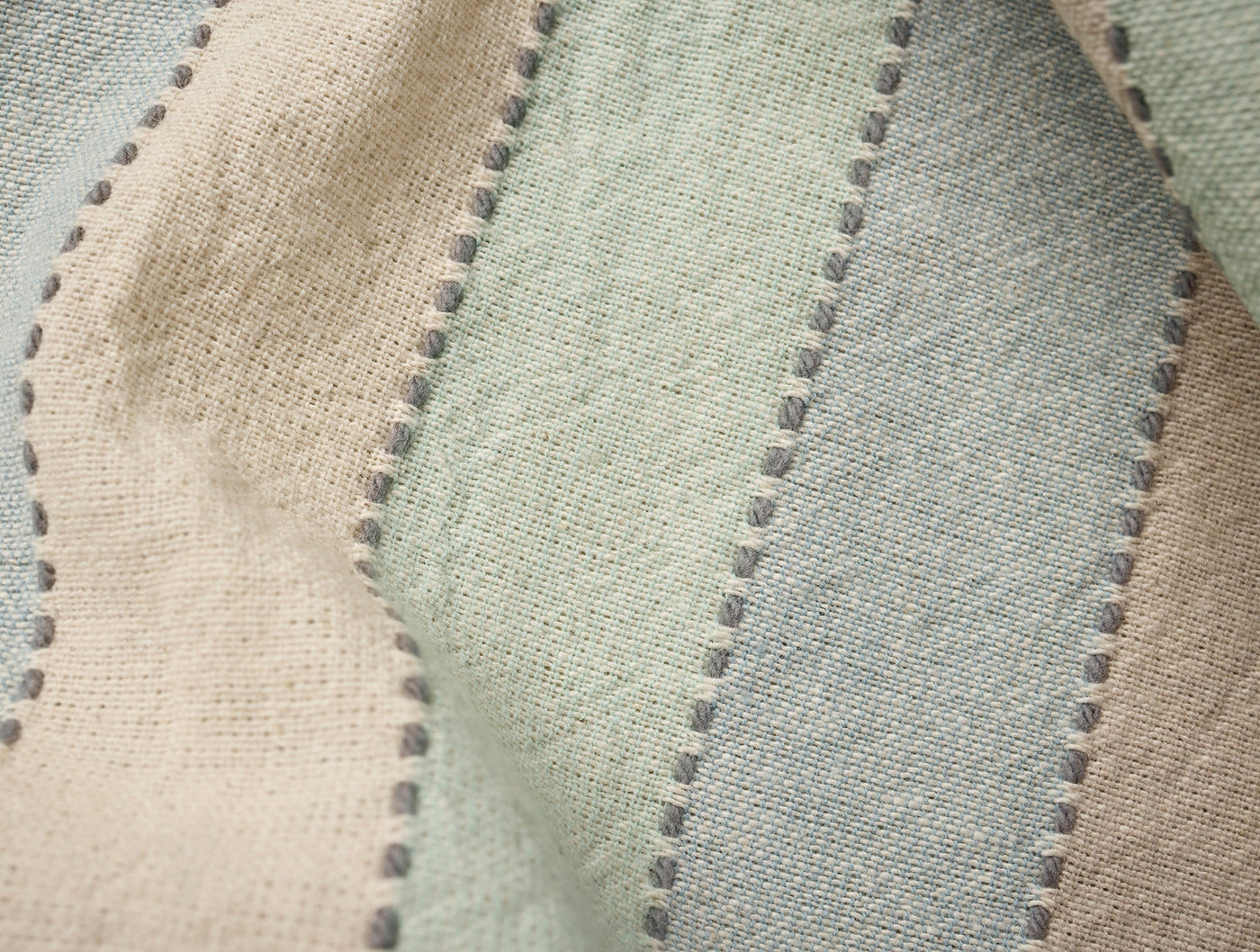 Close-up of Coyuchi Tilden napkin fabric showing dotted stripe weave in sage and sand tones.