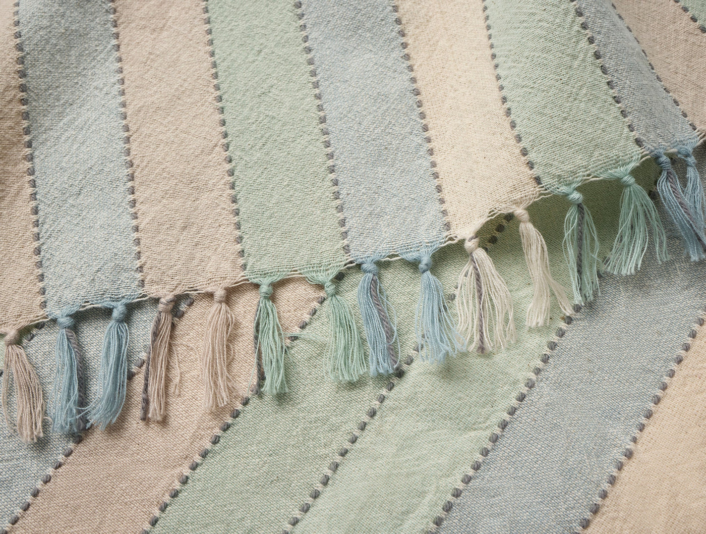 Close-up of Coyuchi Tilden napkin fringe edge in sage, blue, and blush stripes.