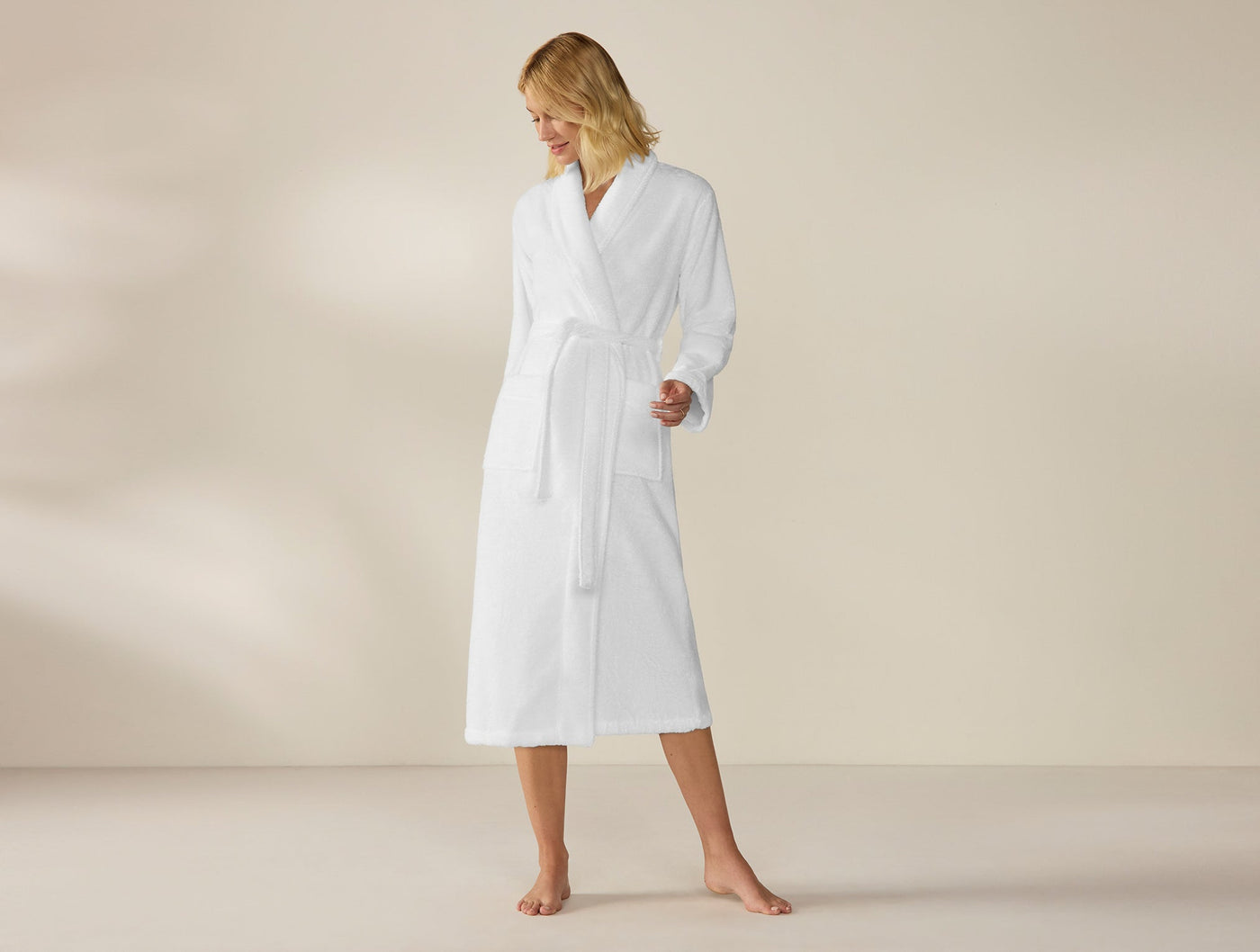 Woman wearing Coyuchi Unisex Cloud Loom robe in white, belted at waist, midi length.