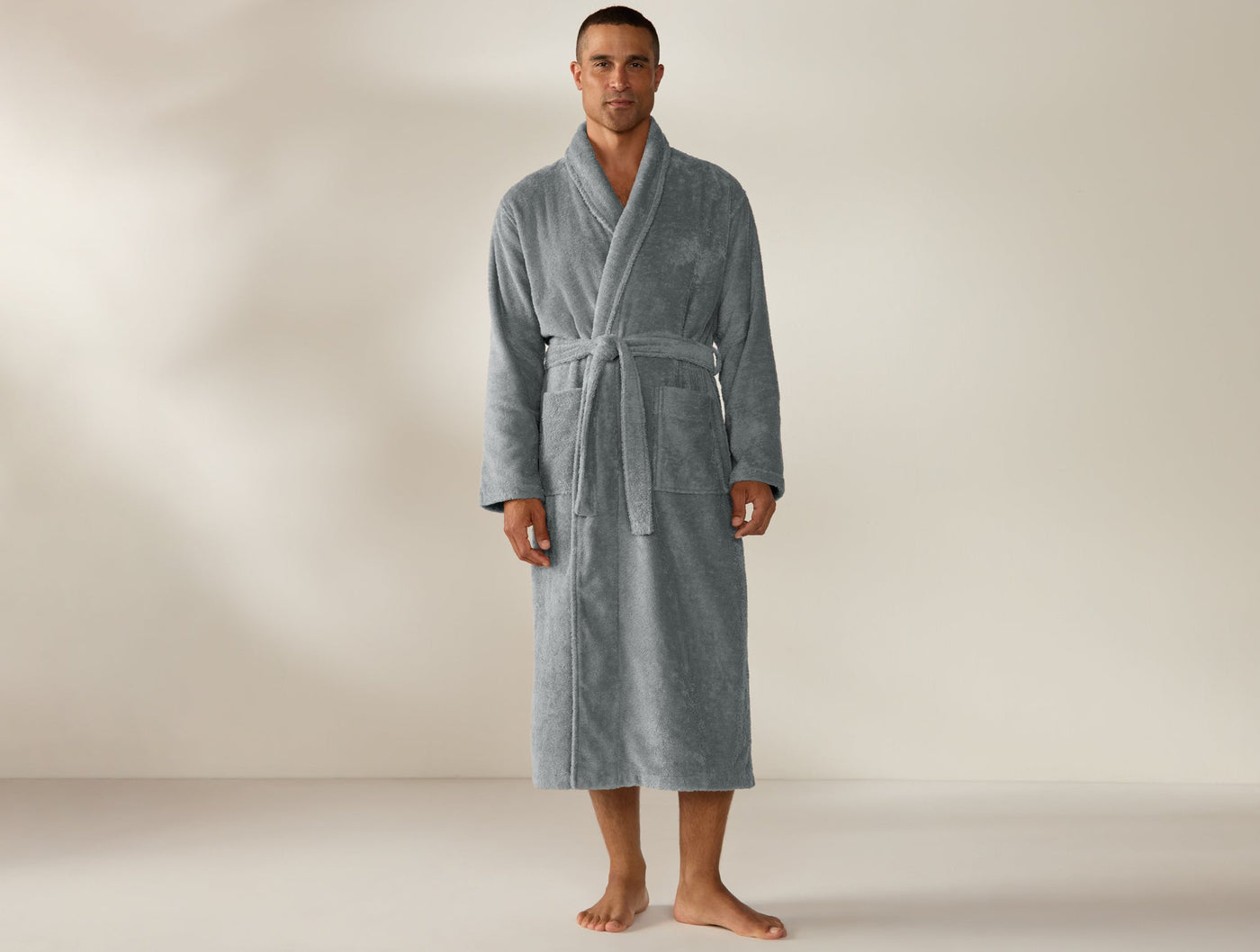 Man wearing Coyuchi Cloud Loom robe in slate grey, full-length front view with tied belt.