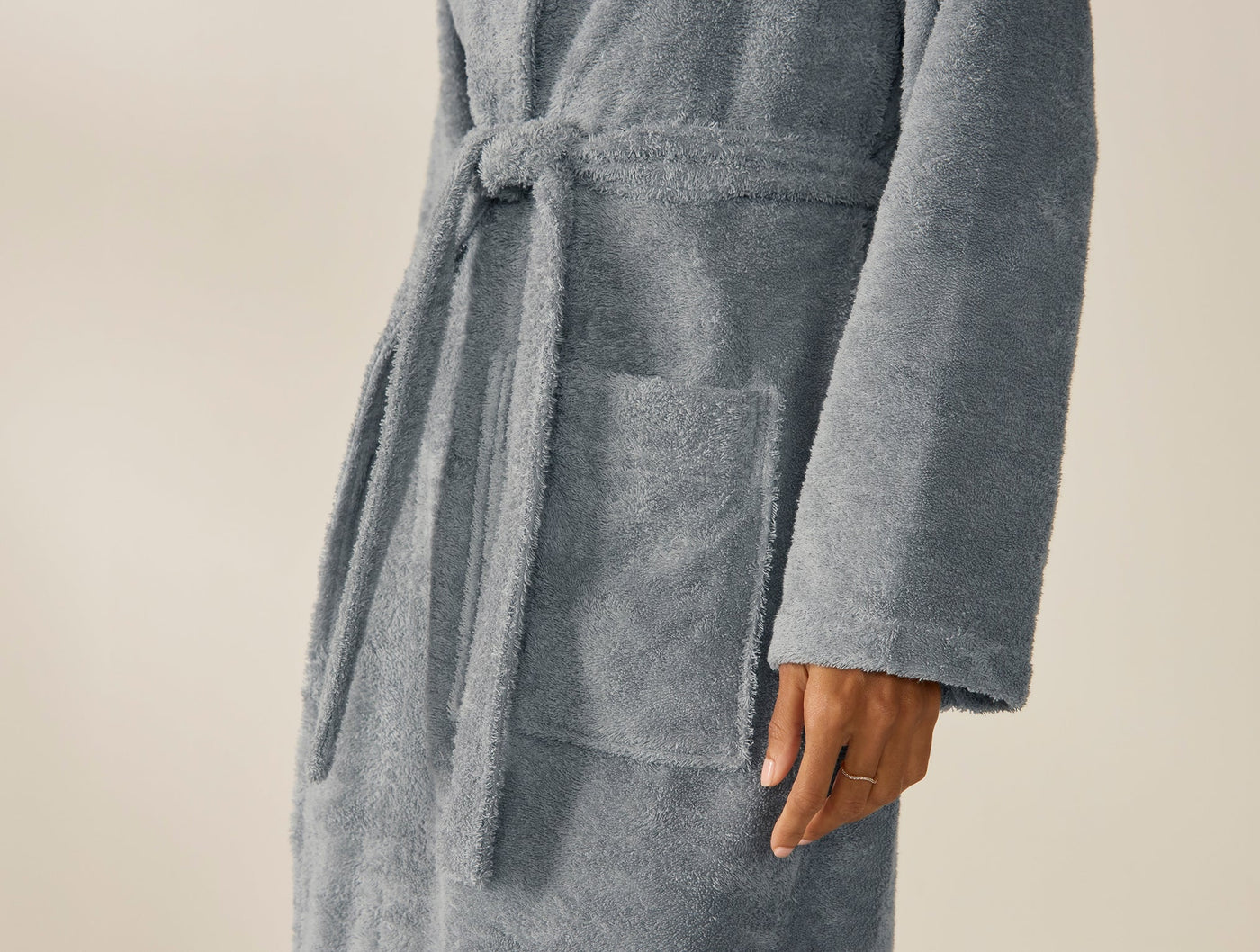 Close-up of slate blue Coyuchi Cloud Loom robe pocket with knotted belt and subtle embroidery.