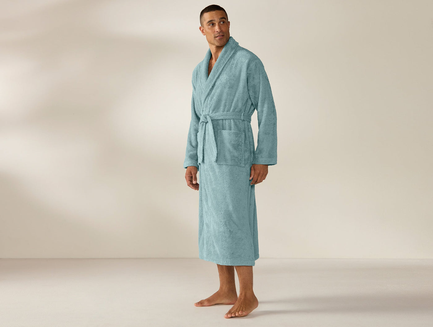 Man wearing Coyuchi Unisex Cloud Loom robe in teal, full-length front view with belted waist.