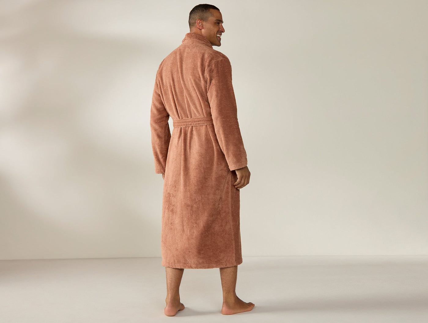Back view of Coyuchi Cloud Loom robe in terracotta, full-length on male model.