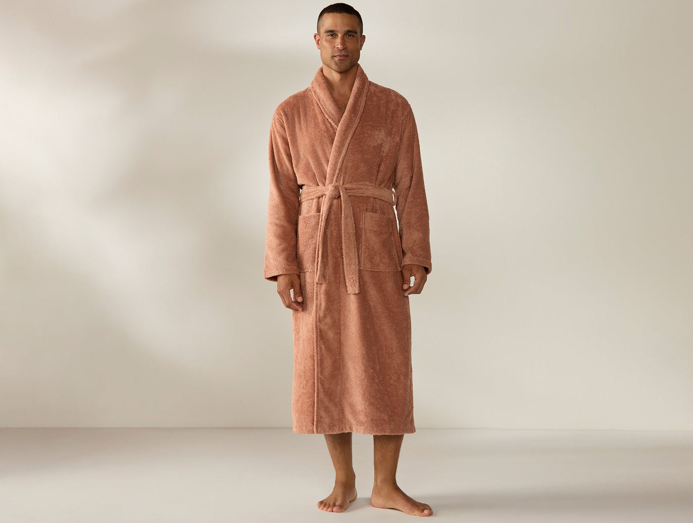 Man wearing Coyuchi Cloud Loom robe in terracotta, full-length front view with tied belt.