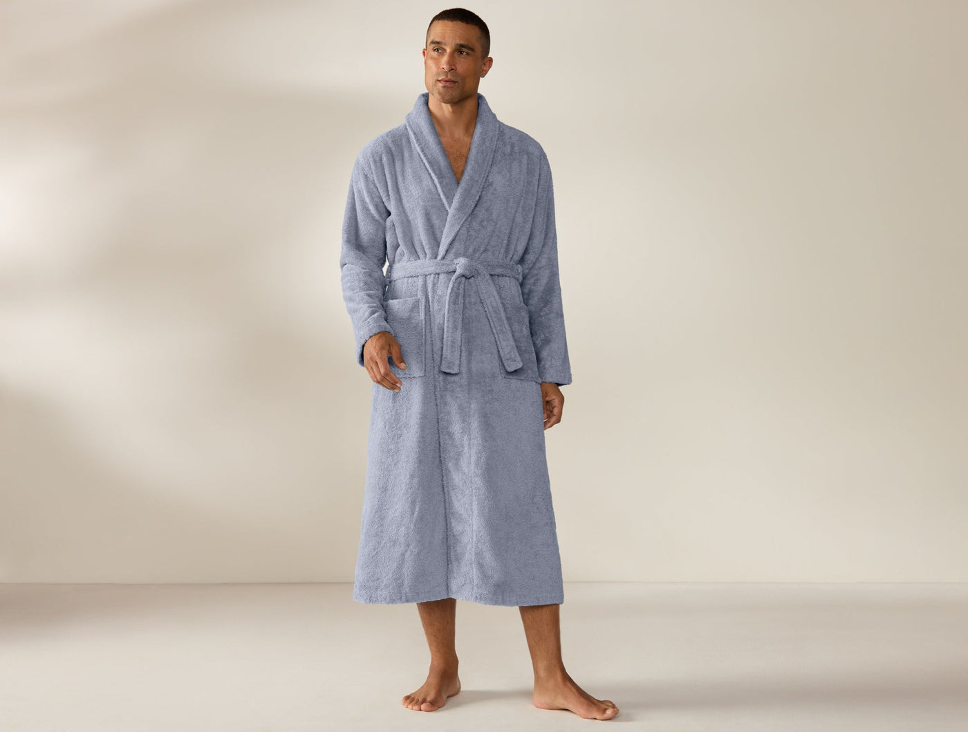 Man wearing Coyuchi Cloud Loom robe in slate blue, full-length front view with belted waist.