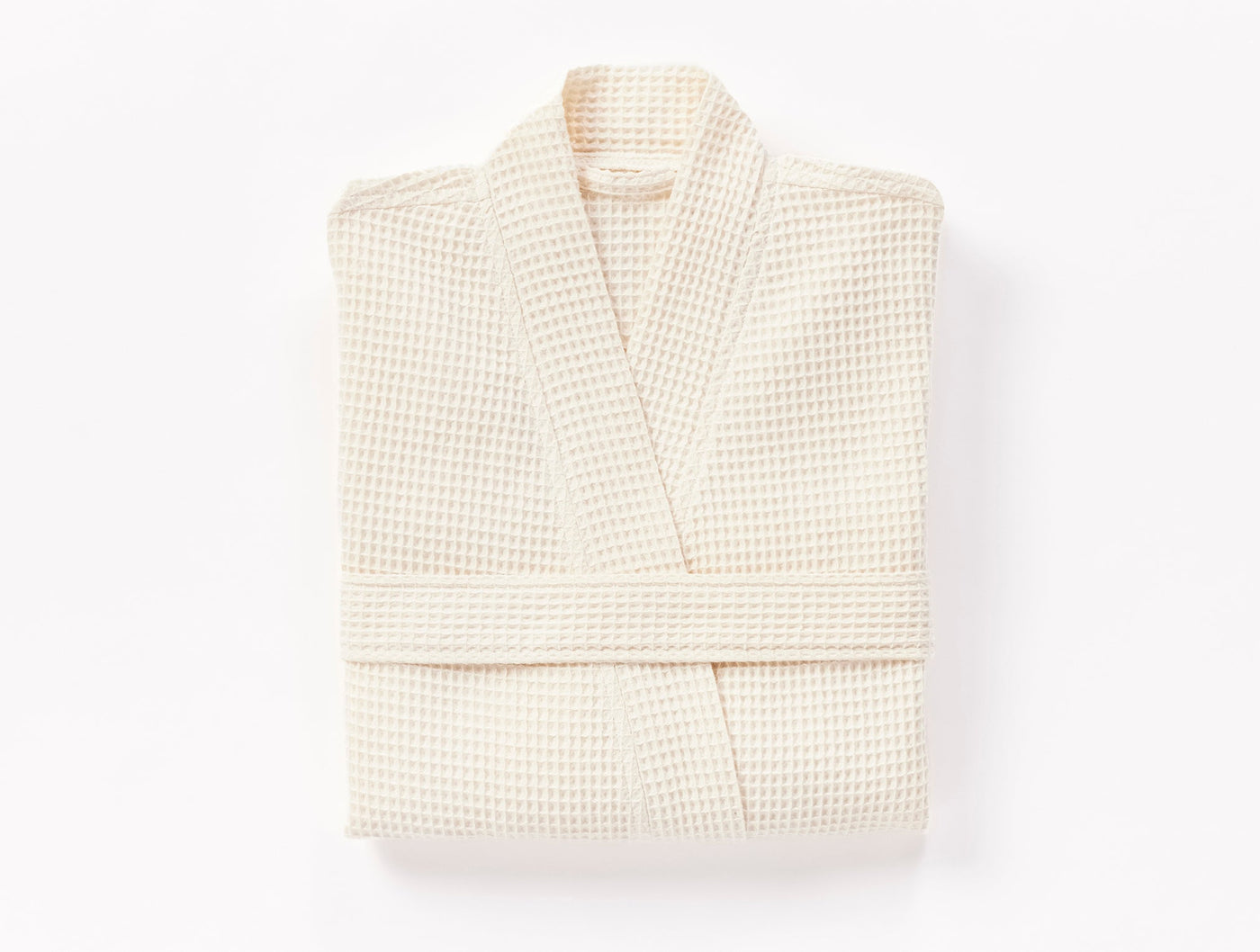 Folded ivory Coyuchi waffle-knit robe with kimono collar and tie belt.