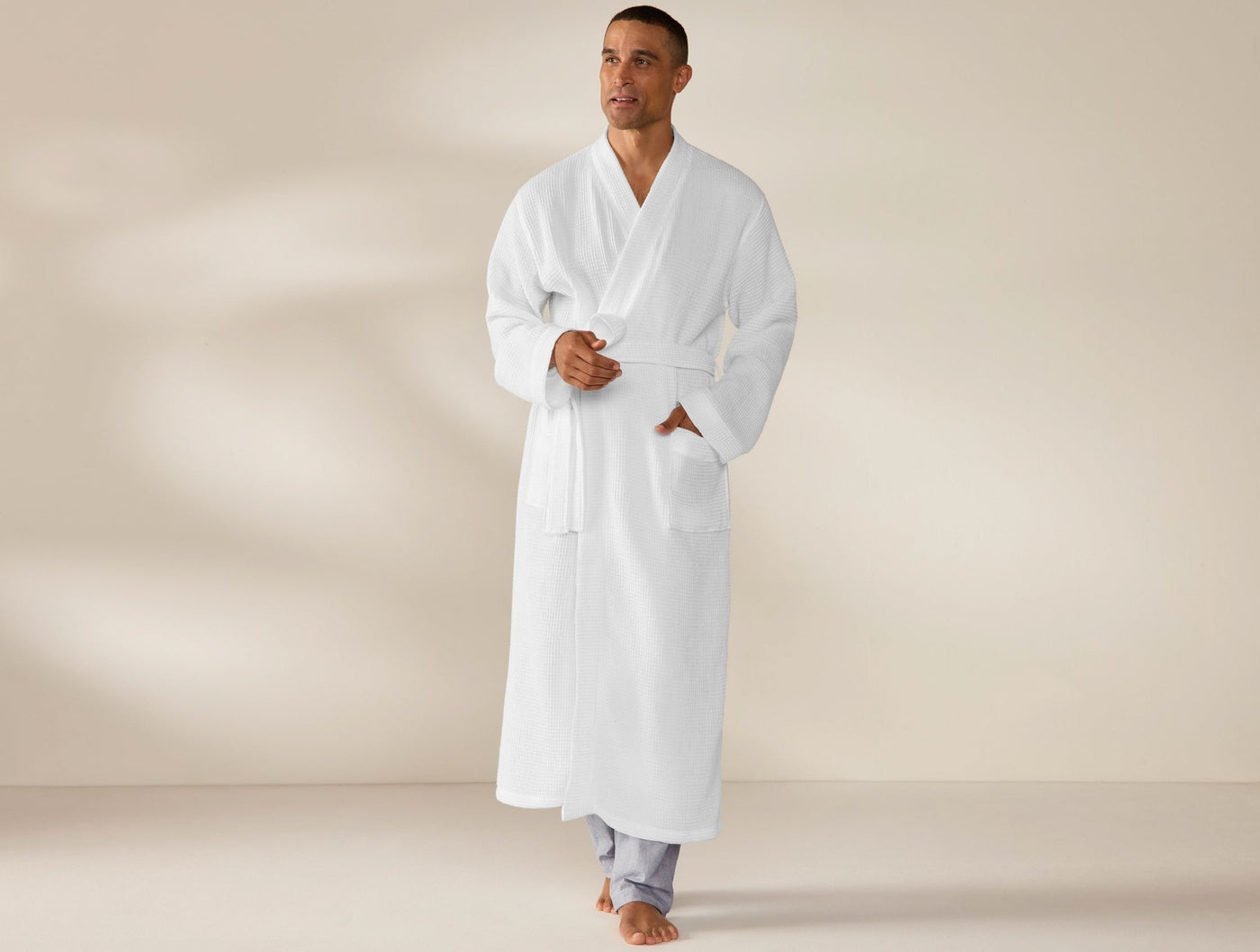Man wearing full-length Coyuchi white waffle-knit robe, belted, front view.