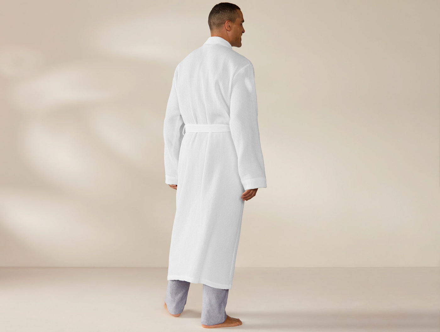 Back view of Coyuchi Unisex Waffle Robe in white, full-length on male model.