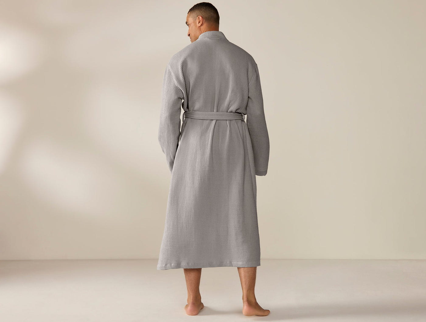 Rear view of a slate grey waffle-textured robe with belted waist, worn by a male model.