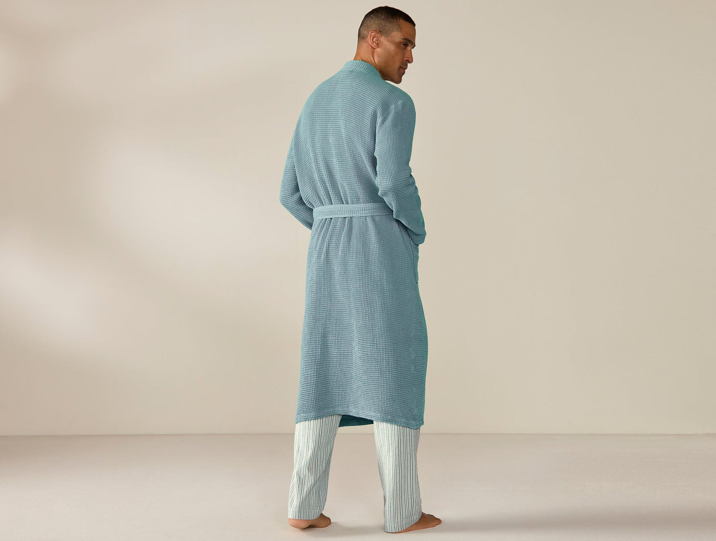 Back view of Coyuchi Unisex Waffle Robe in teal, belted, full-length, on male model.