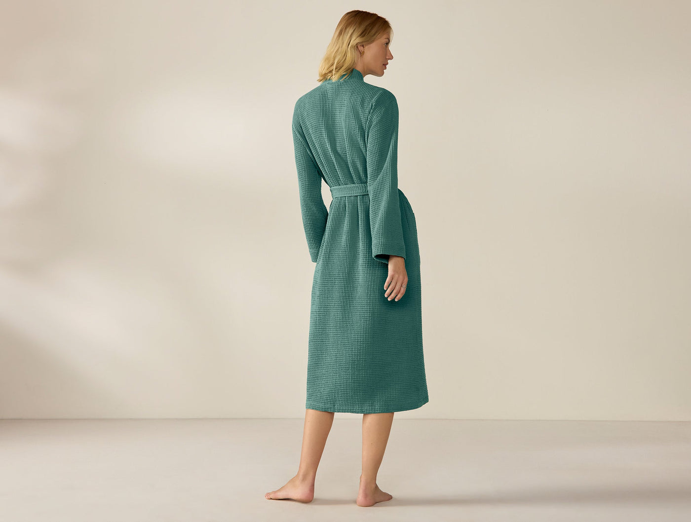 Back view of Coyuchi Unisex Waffle Robe in teal, full-length on female model.