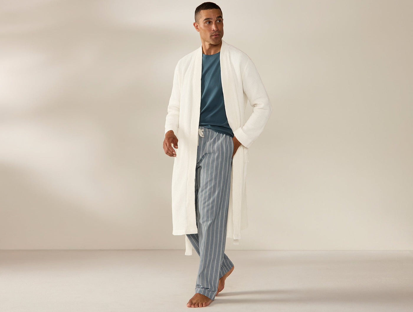 Coyuchi ivory waffle-knit robe worn open over teal top and striped pants, full-length view.