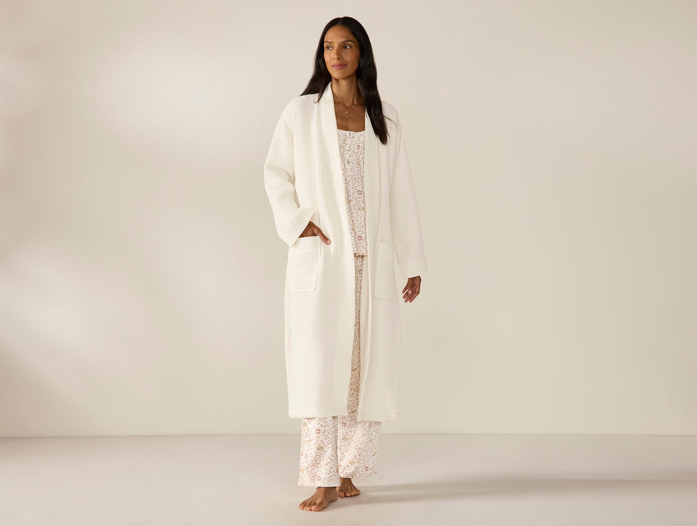 Model wearing Coyuchi ivory waffle-knit robe, full-length, over floral pajamas.