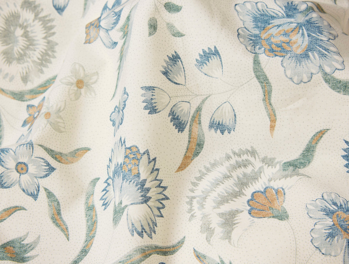 Close-up of Coyuchi Viola Print duvet cover showing blue, sage, and amber floral print on ivory.