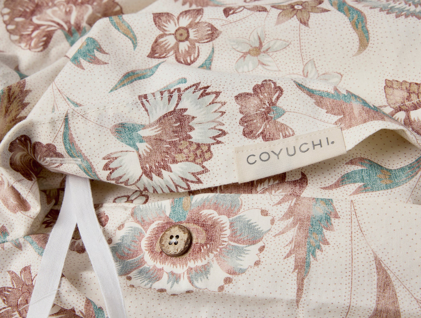Close-up of Coyuchi Viola Print duvet cover button closure, ivory with floral print.