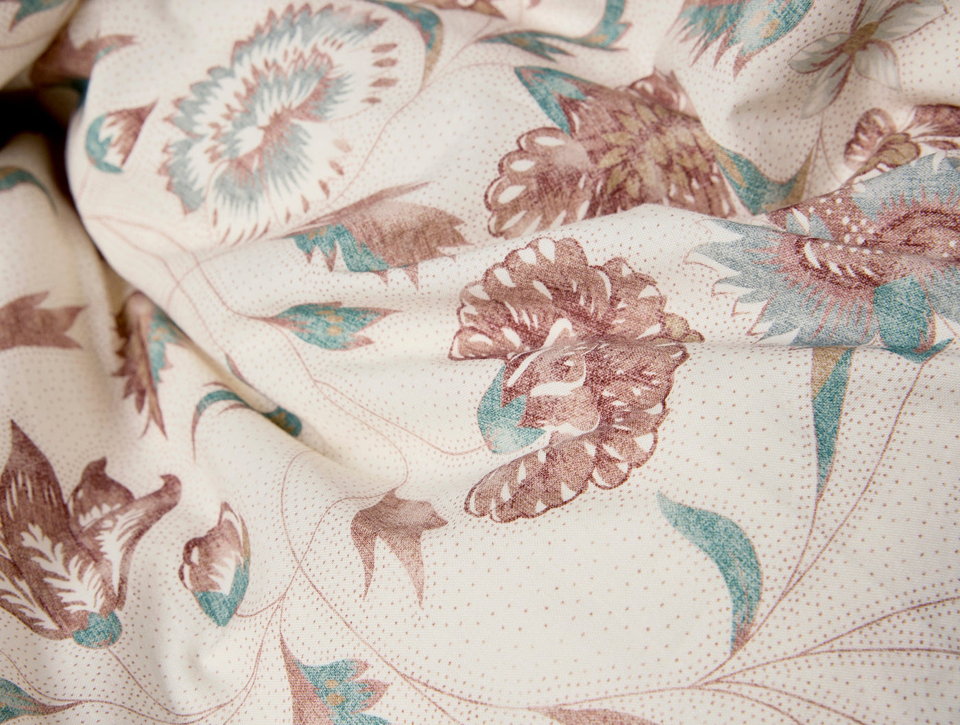 Close-up of Coyuchi Viola Print duvet cover showing mauve and teal floral pattern on ivory.