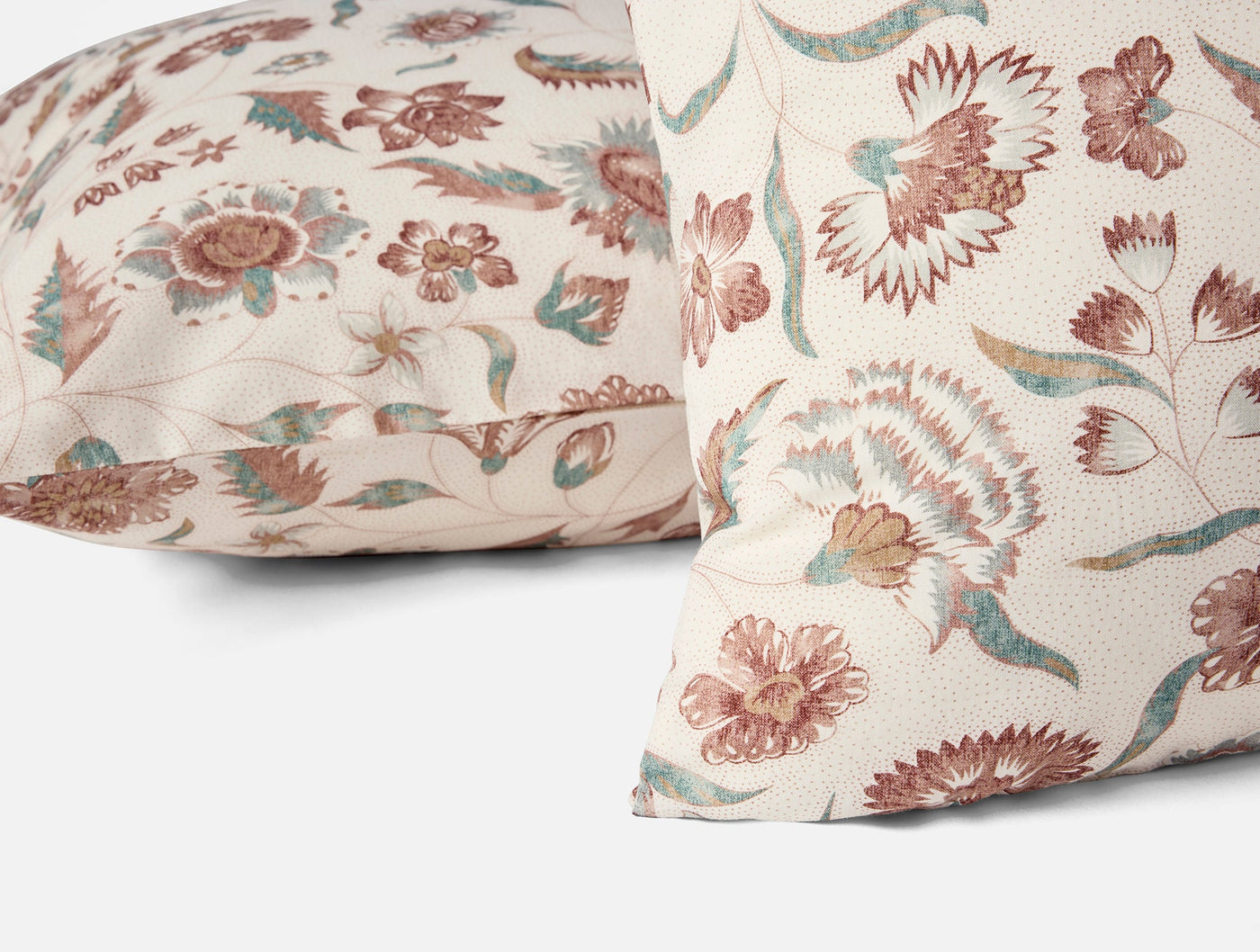 Close-up of two Viola Print shams showing rose and teal floral pattern on ivory cotton.