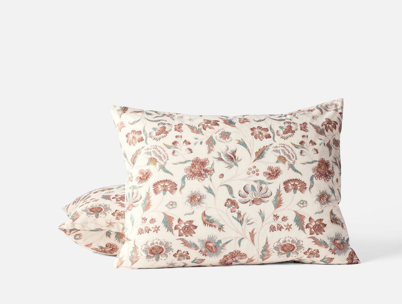 Terracotta and sage floral print on ivory cotton pillowcase, two shams stacked.