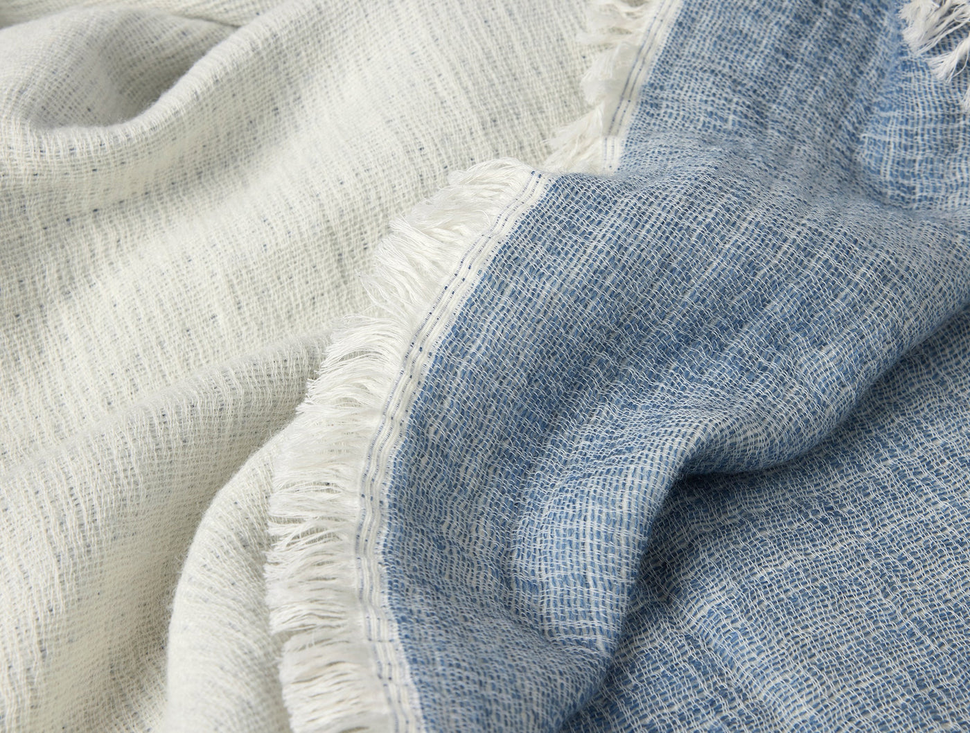 Close-up of Coyuchi Willow throw showing ivory and sky blue woven textures with fringe edge.