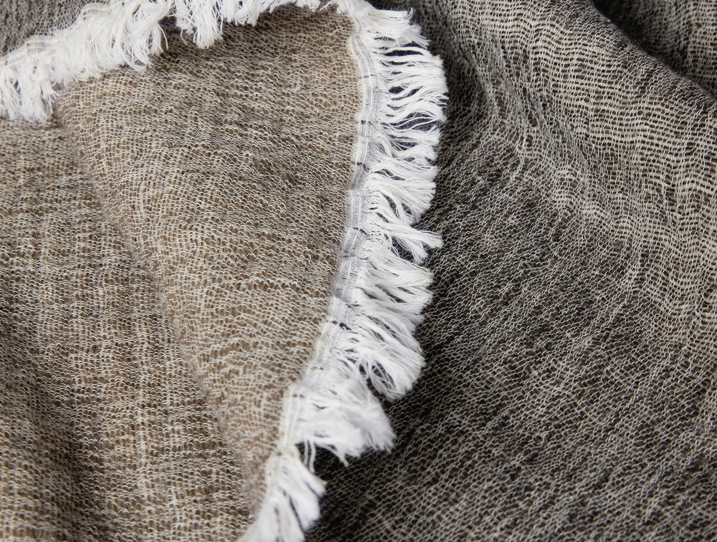 Close-up of Coyuchi Willow throw's fringe edge, showing contrast between natural and charcoal sides.