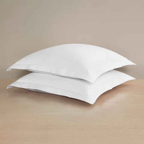 Two white Waves | Pique Euro Sham pillows by Frette stacked on wood, set against a beige background, showcasing premium hotel-quality cotton comfort.