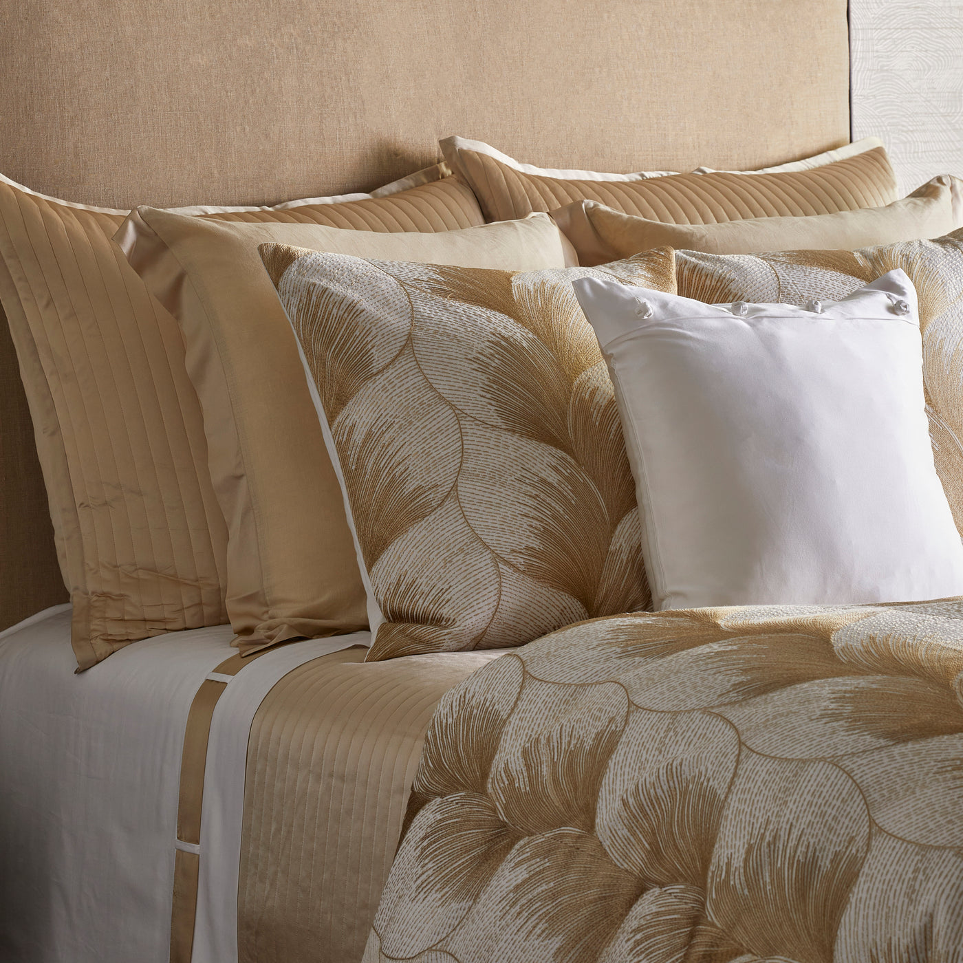 Close-up of Ann Gish Fan duvet cover in gold, with layered pillows in a styled bedroom.