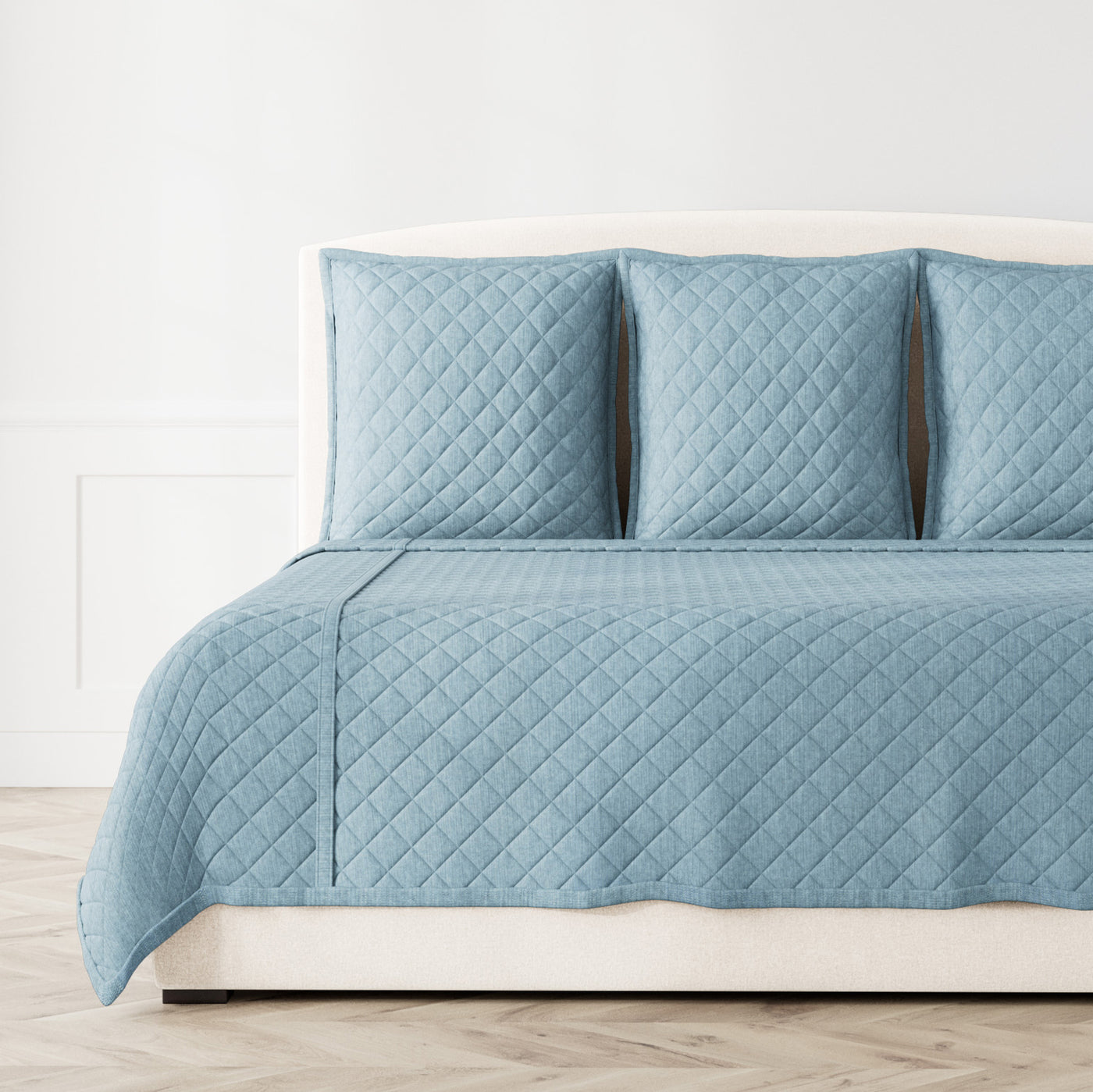 Ann Gish Faux Linen coverlet set in slate blue, diamond quilting, styled on bed with matching shams.