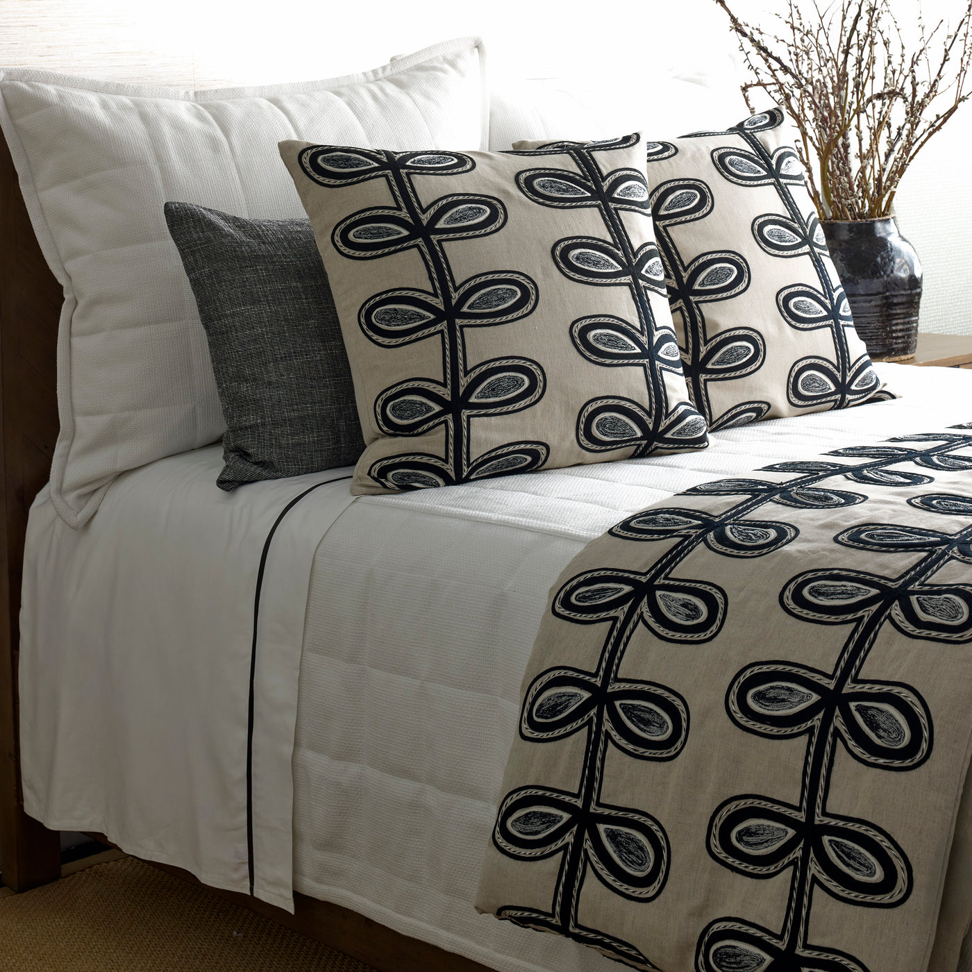 Ann Gish Fellini pillows styled on bed with matching coverlet in ivory and black botanical print.