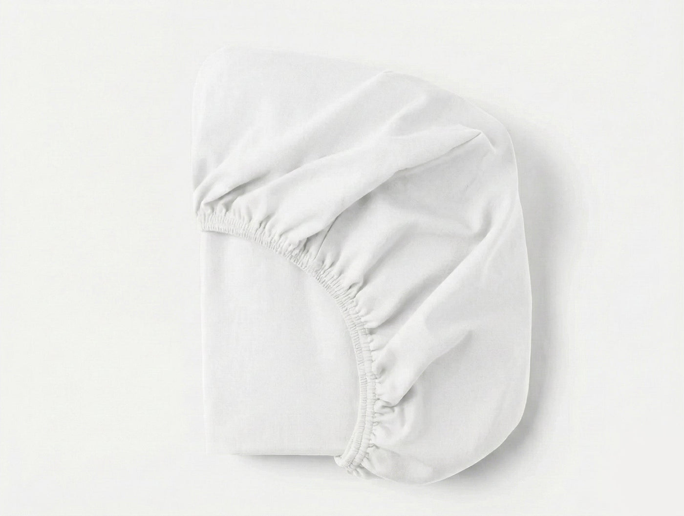 Coyuchi Cloud Brushed Flannel fitted sheet in white, folded to show elasticated corners.