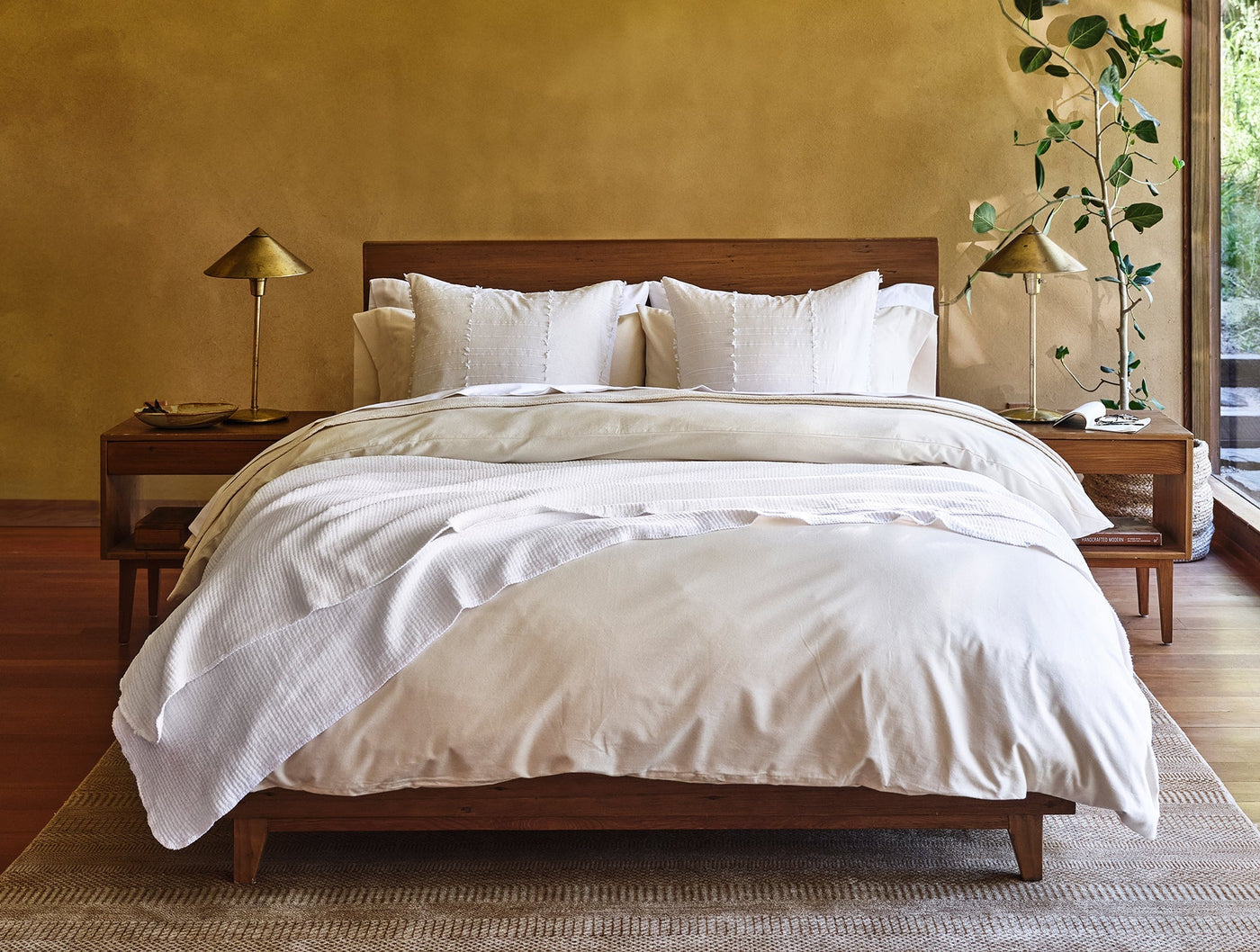 Ivory flannel sheet set on a wood-framed bed with warm ochre wall and natural accents.
