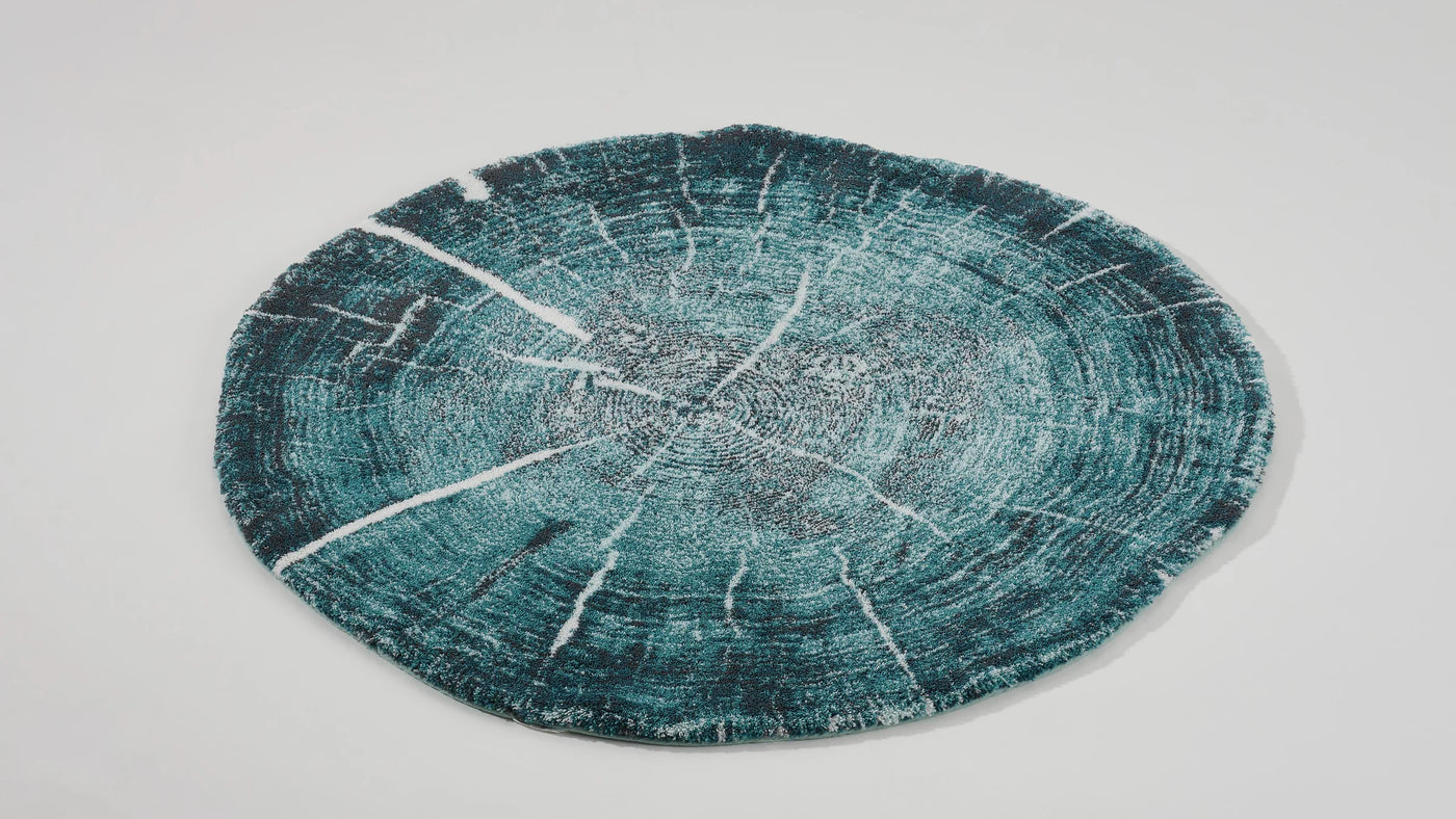 Close-up of teal and silver tree-ring pattern on Fossile round bath rug.
