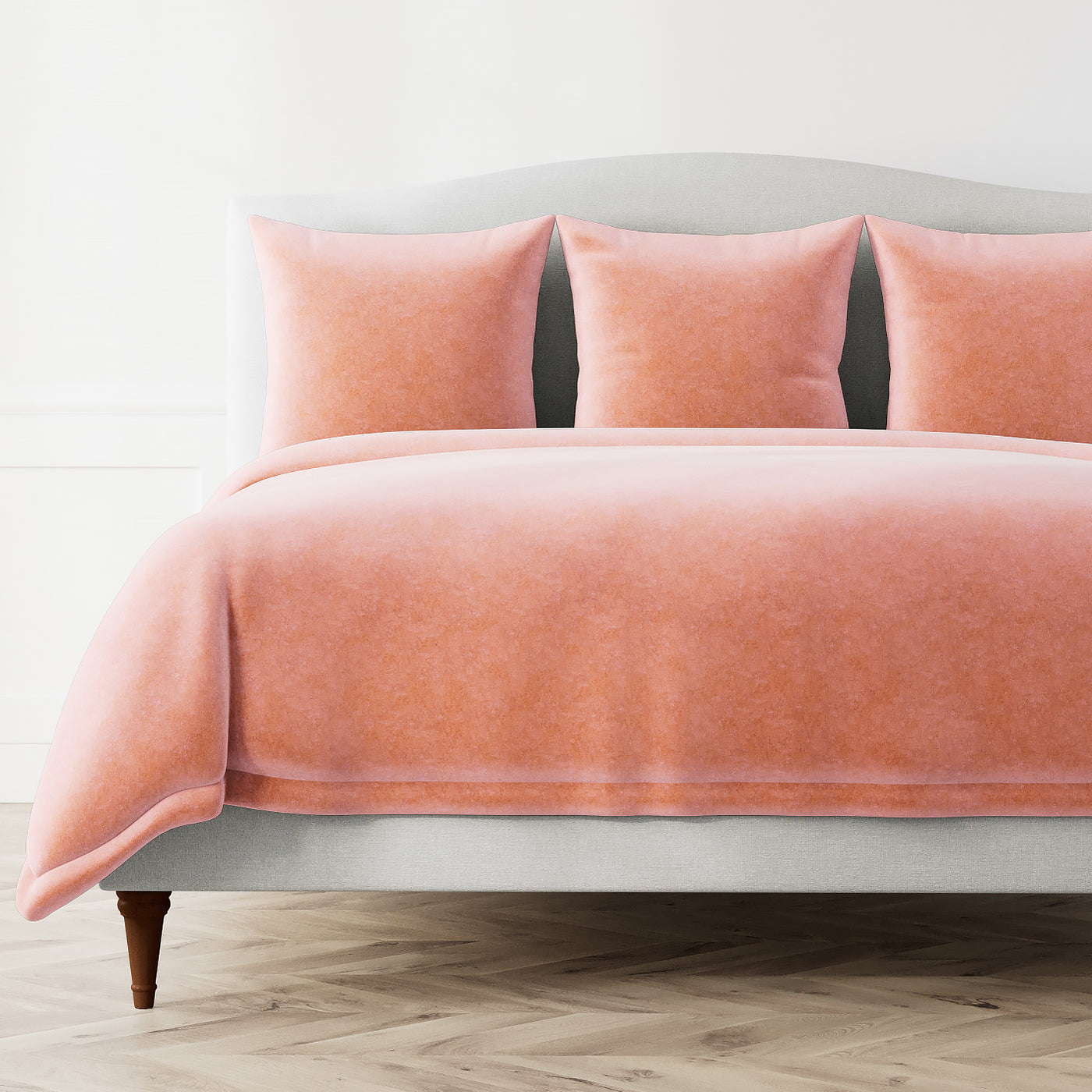 Ann Gish Fresco Velvet duvet cover in coral, styled on bed with matching shams.