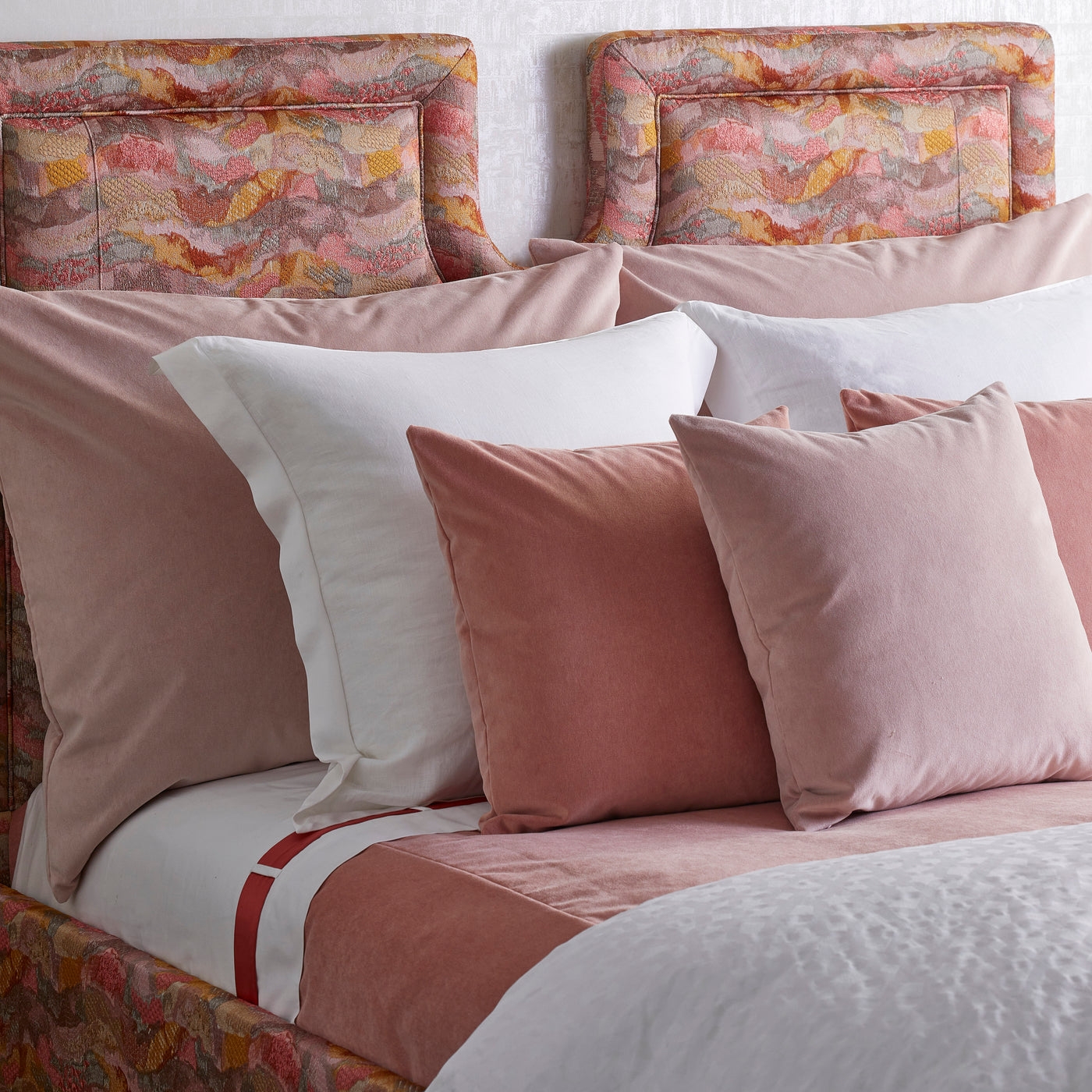 Dusty rose velvet Euro shams and pillows layered on a styled bed with floral headboard.
