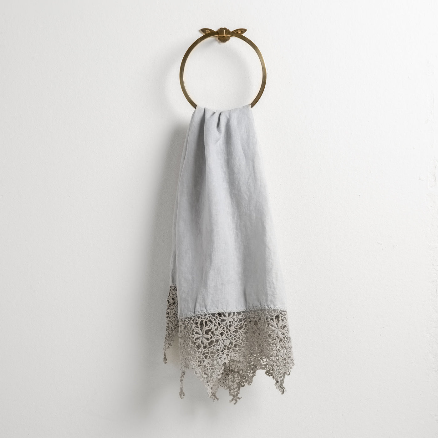 Cloud Frida guest towel draped on brass ring, lace trim detail at hem.