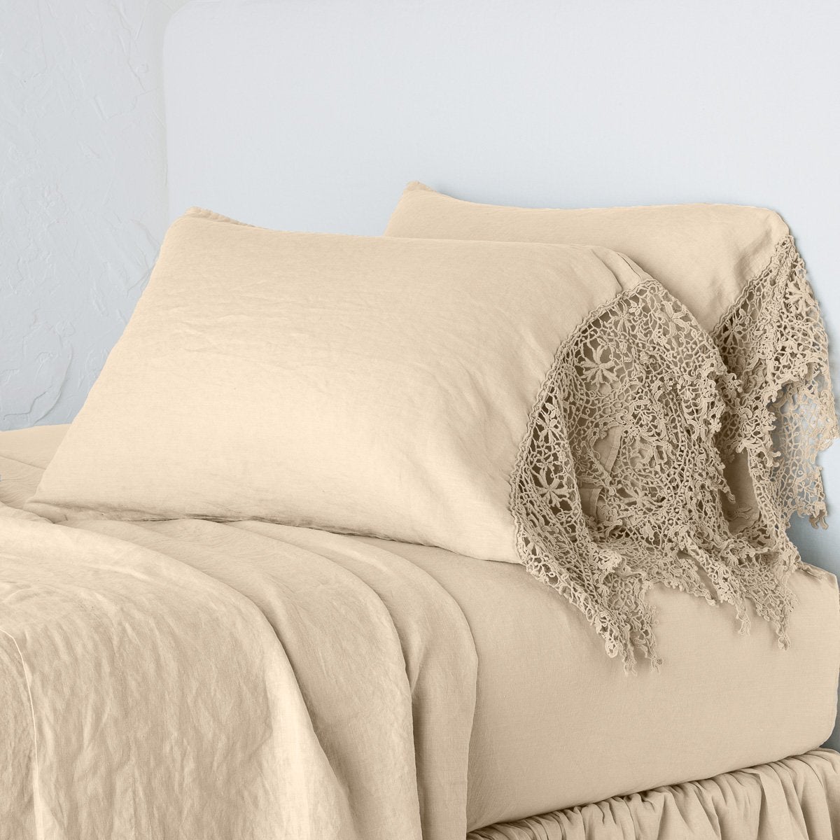Honeycomb linen pillowcase with crochet lace trim, styled on a made bed.