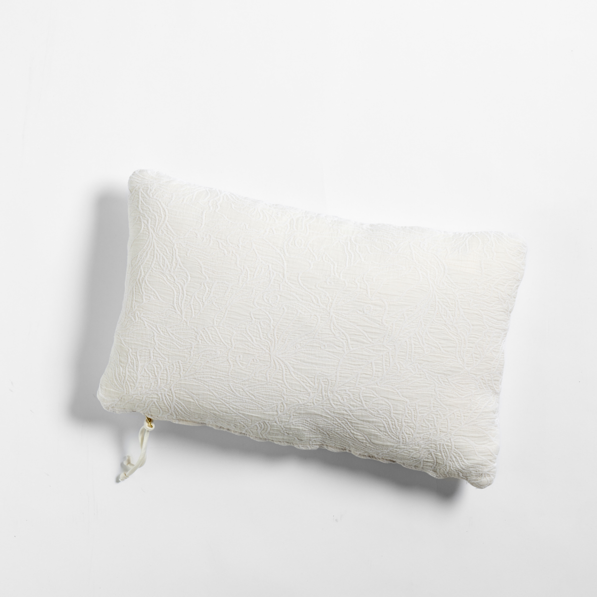 Georgia throw pillow in Natural, showing textured matelassé weave and tassel detail.