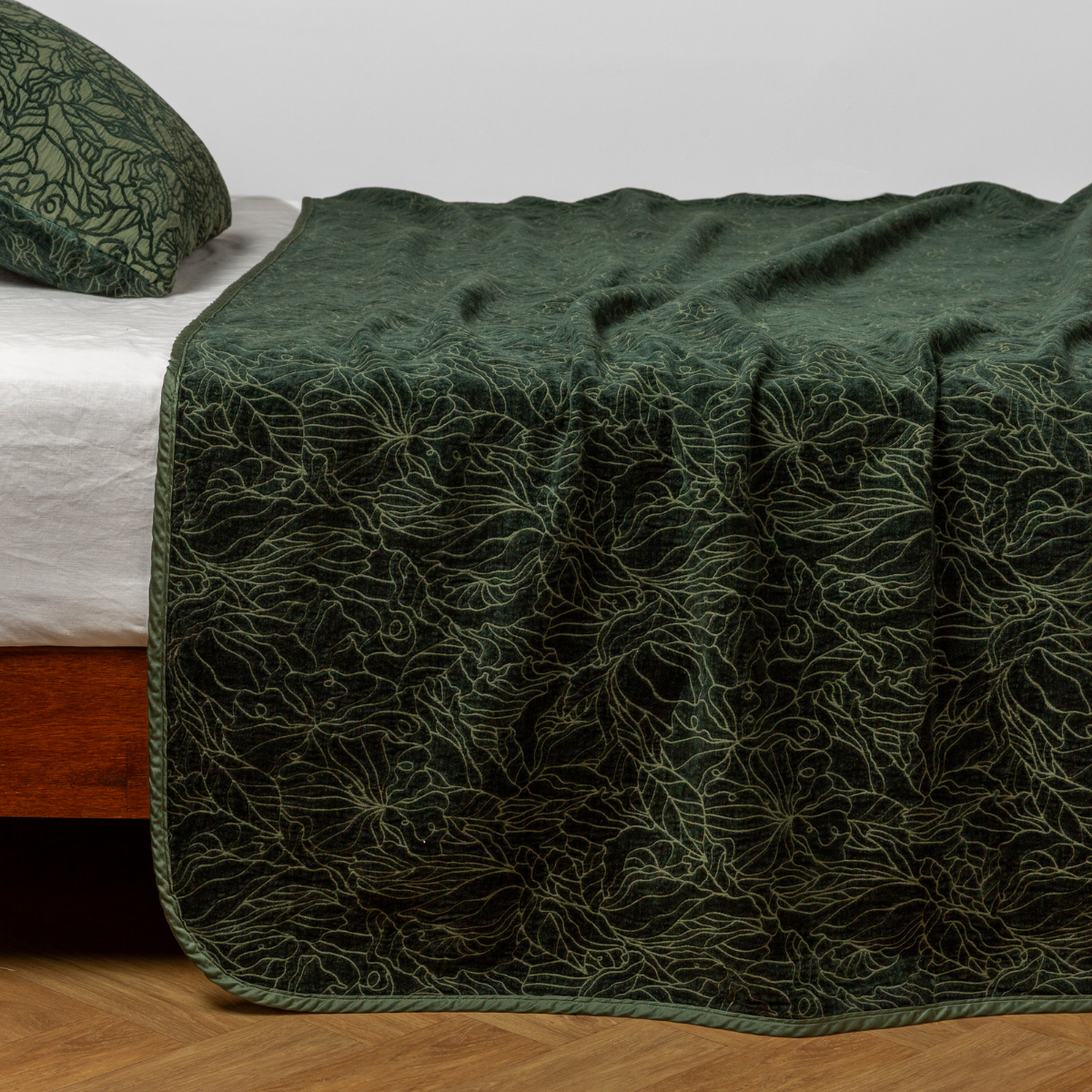 Bella Notte Georgia bedspread in Juniper draped over bed, floral embroidery detail visible.