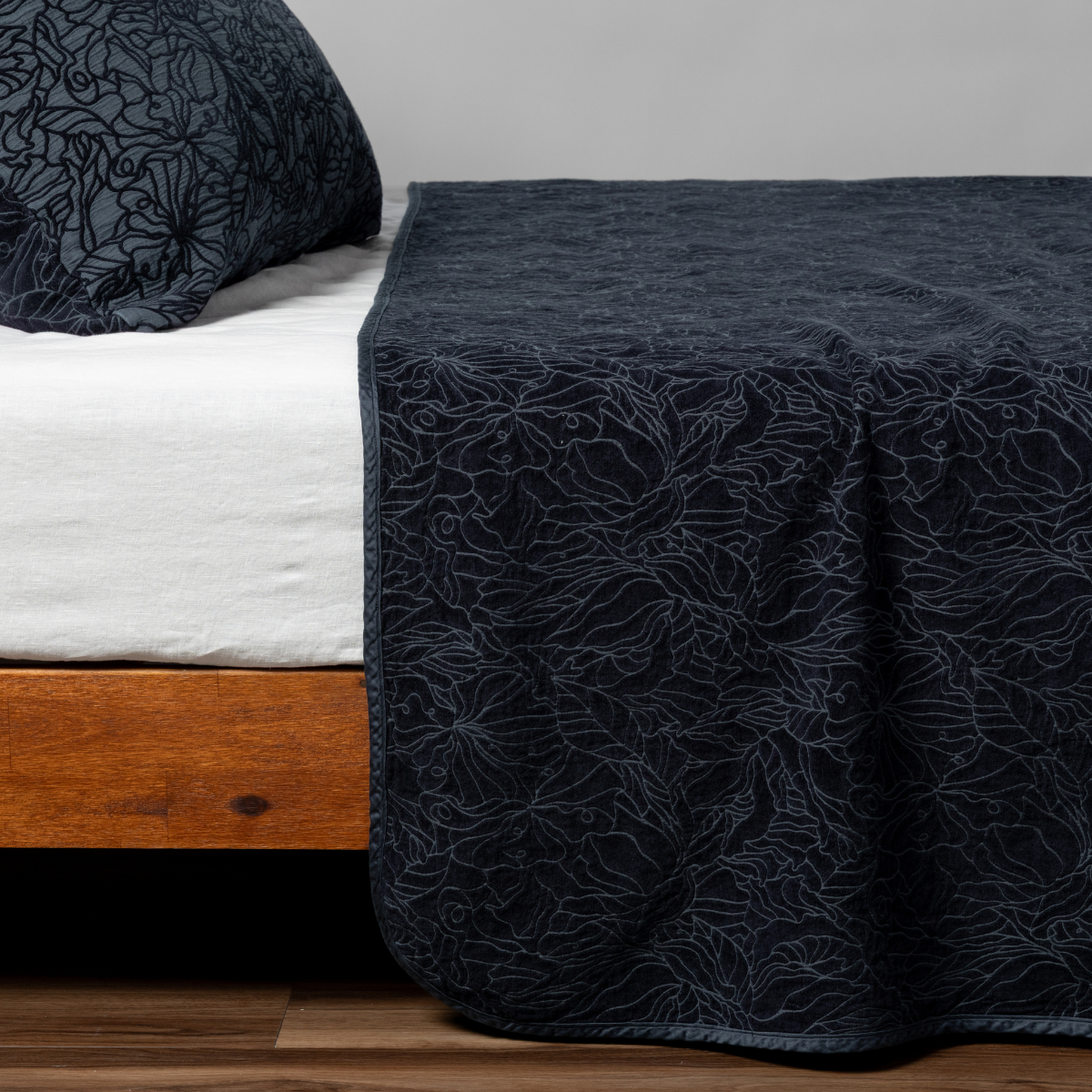Close-up of Bella Notte Georgia bedspread in Slate with embroidered floral pattern draped over bed.