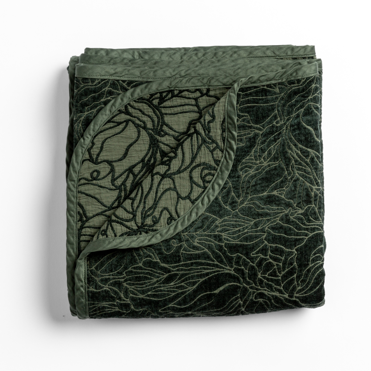 Folded Juniper Georgia blanket corner turned back, revealing botanical embroidery on velvet.