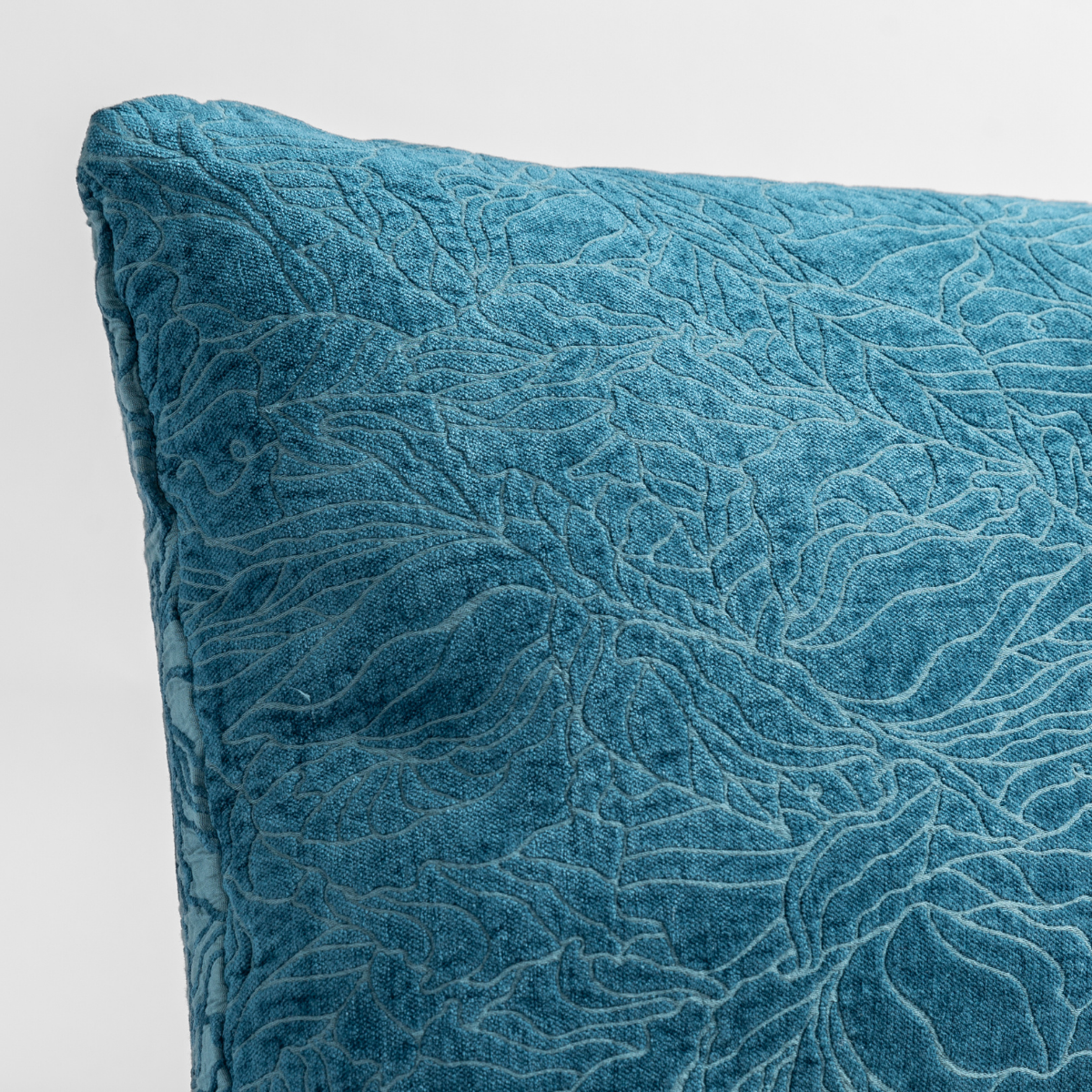 Close-up of Cenote velvet throw pillow corner showing intricate floral quilted texture.