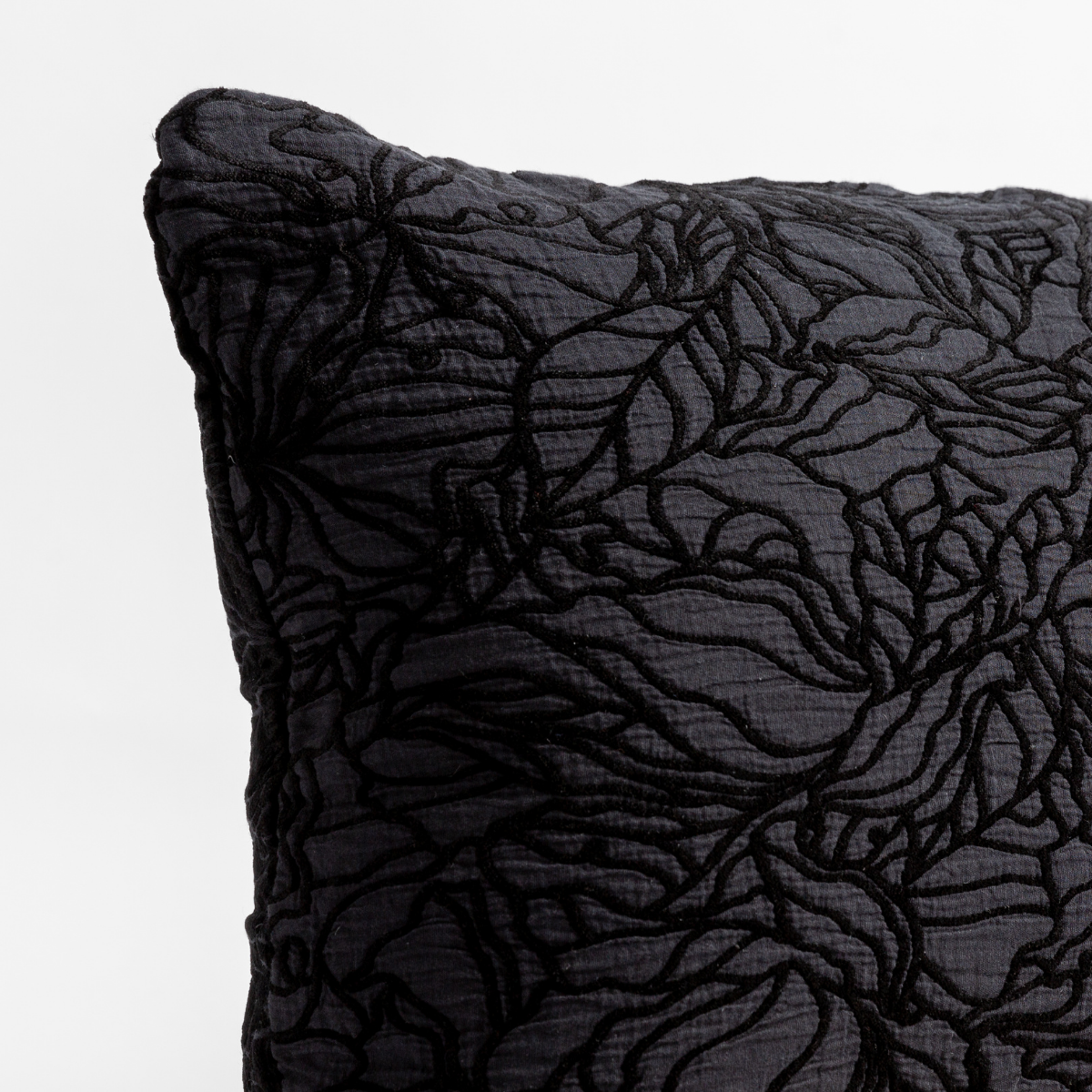 Close-up of Corvino Georgia throw pillow corner showing raised floral embroidery on textured black fabric.