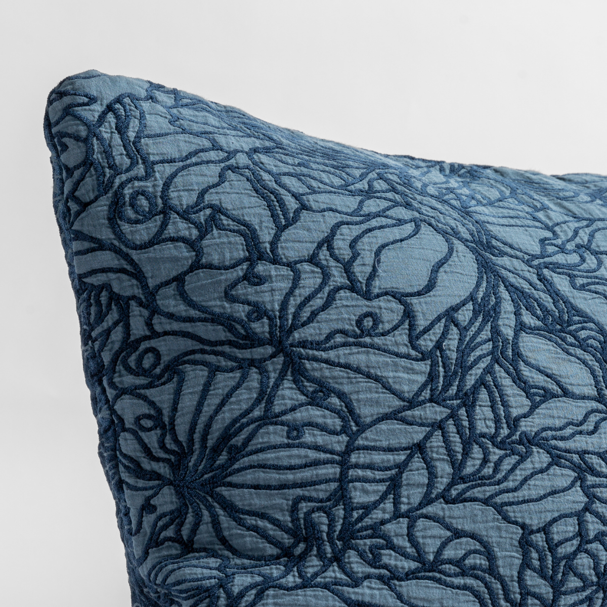 Close-up of Midnight Georgia sham corner, dark floral embroidery on blue linen fabric.