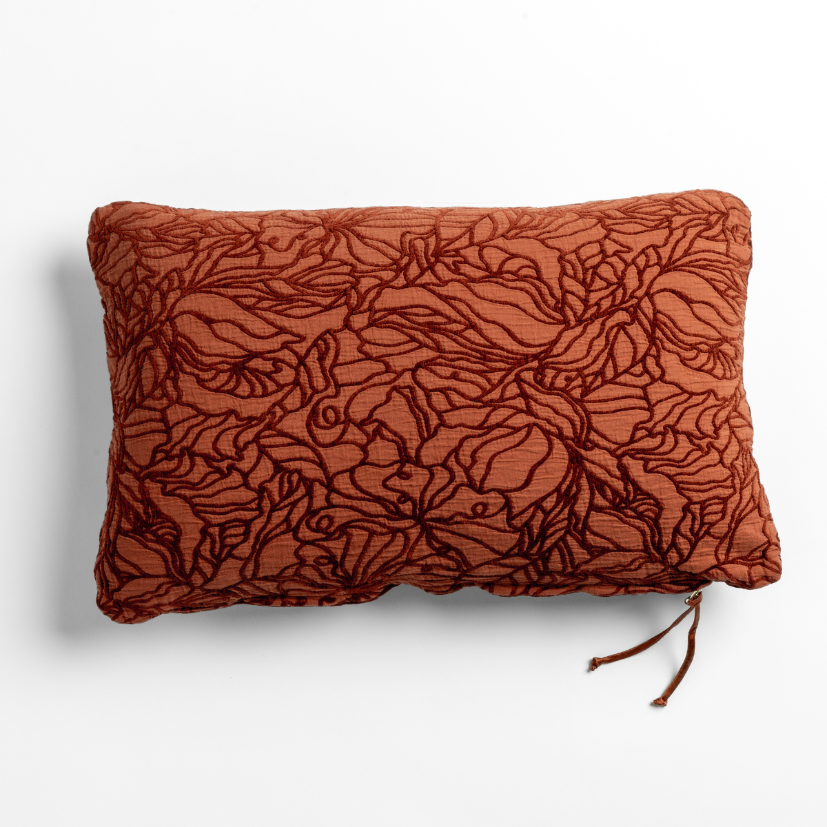 Autumn Georgia throw pillow with dark floral embroidery on textured rust linen, tassel zip detail.