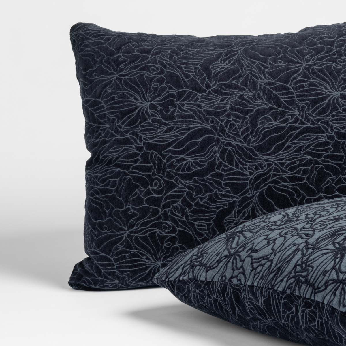 Close-up of Bella Notte Georgia sham in Slate, showing embroidered floral line pattern on deep navy fabric.