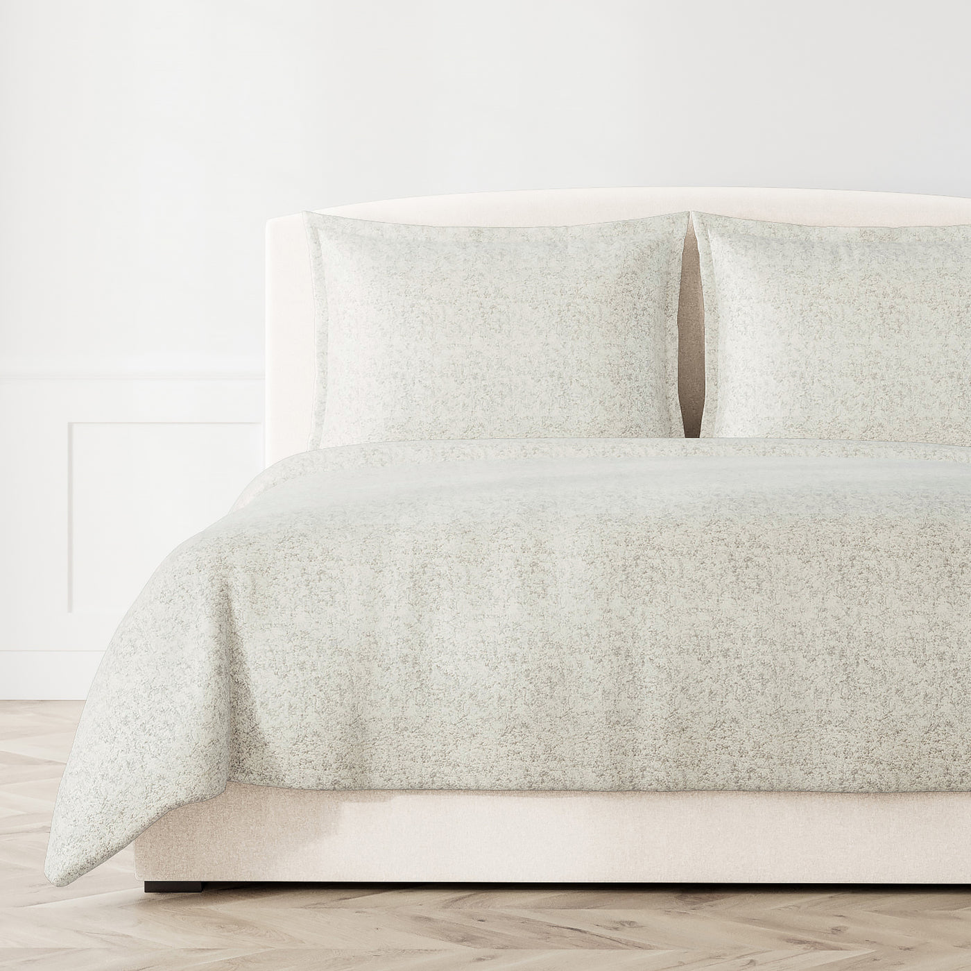 Ann Gish Glacier coverlet in ivory, styled on a bed with matching shams, subtle allover pattern.