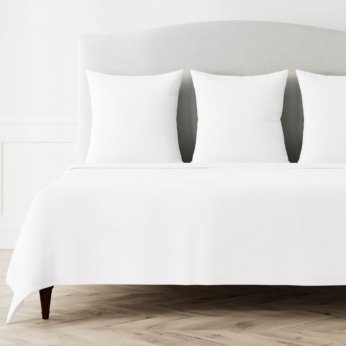 Crisp white coverlet set styled on a bed with matching pillow shams, full bed view.