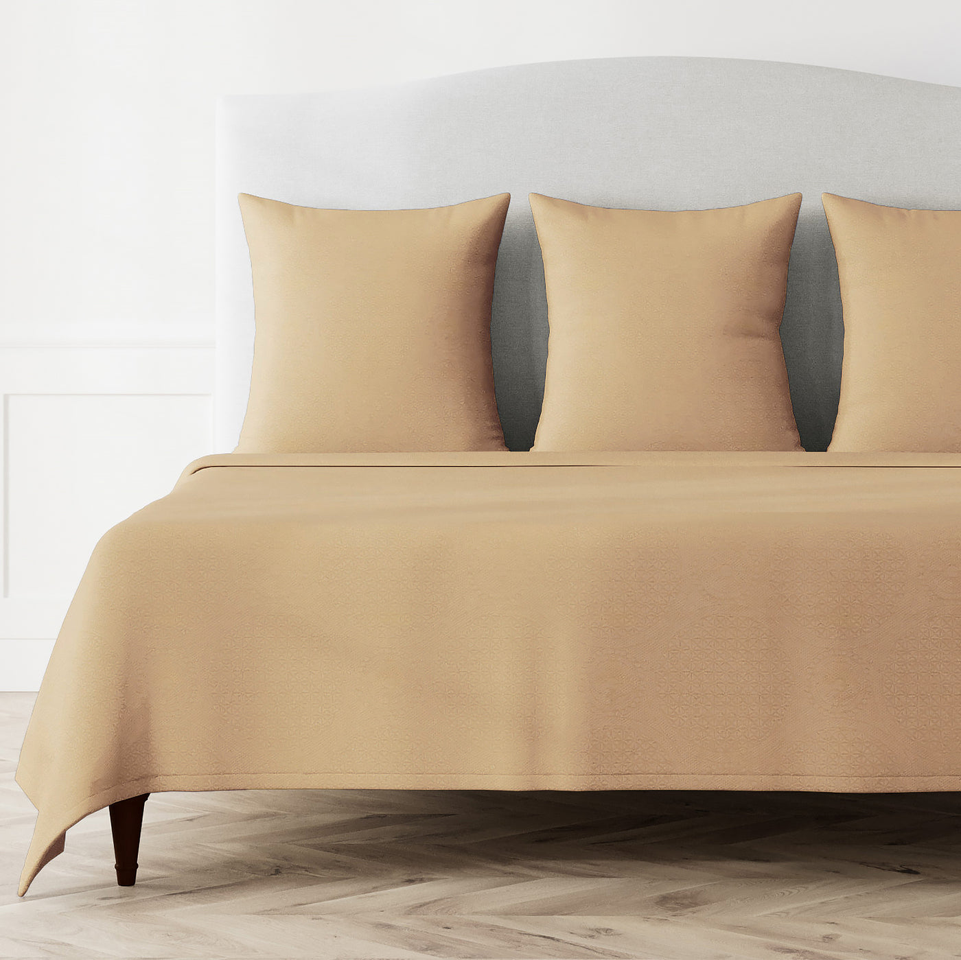 Warm champagne coverlet and matching shams styled on a bed, showing full spread and drape.