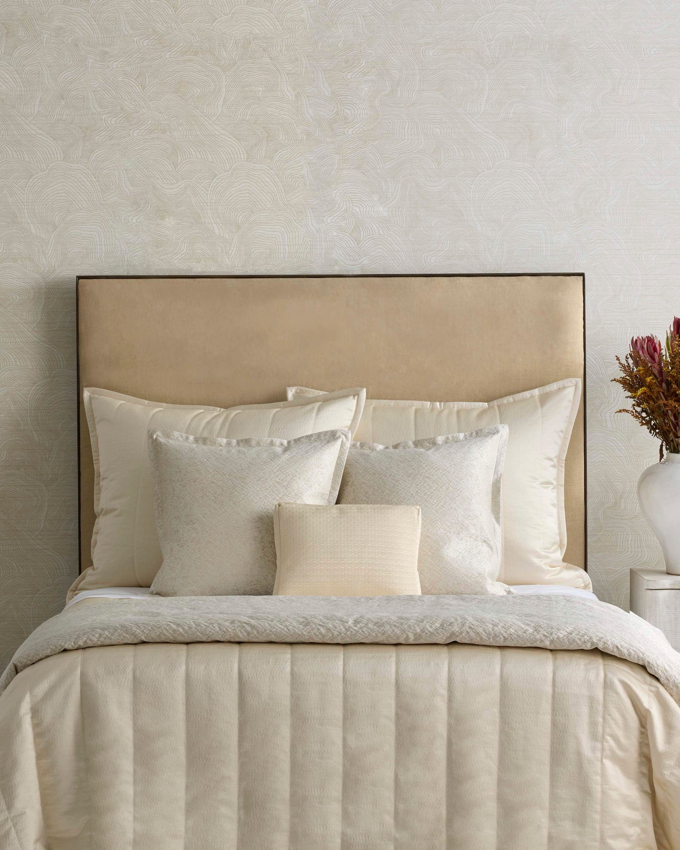 Ann Gish Hammered pillow in ivory, styled on a neutral bed with layered bedding.