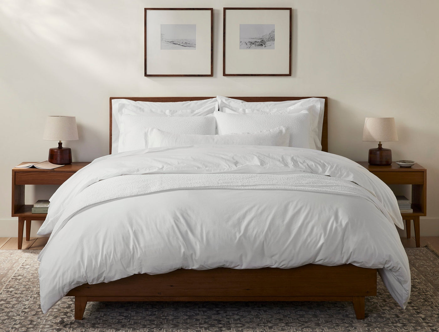 Coyuchi Heritage Percale white shams styled on a made bed with duvet in warm bedroom setting.