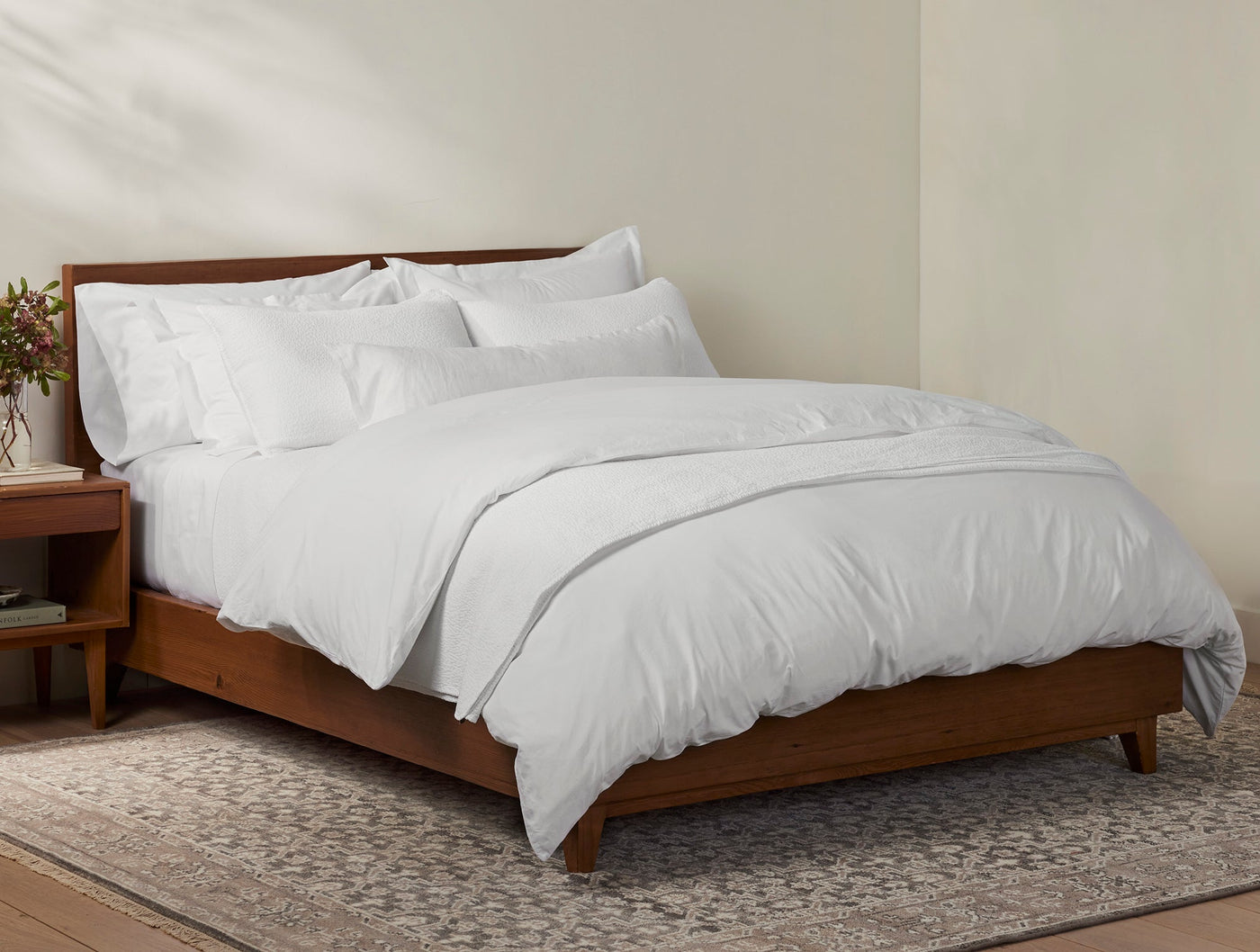 Coyuchi Heritage Percale shams styled on a made bed with white duvet and walnut frame.